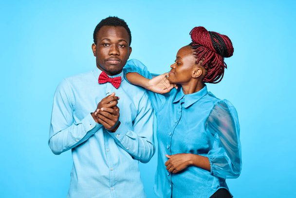 young beautiful couple posing in studio on blue background - Photo, Image