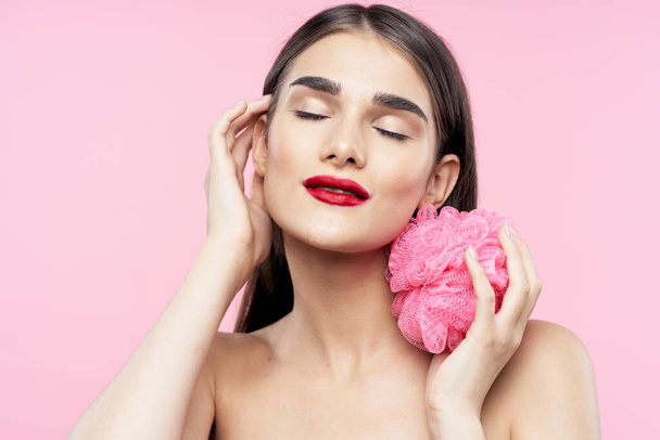 Bőrápolás és szépség. Portré fiatal gyönyörű nő mosóronggyal rózsaszín háttér - Fotó, kép