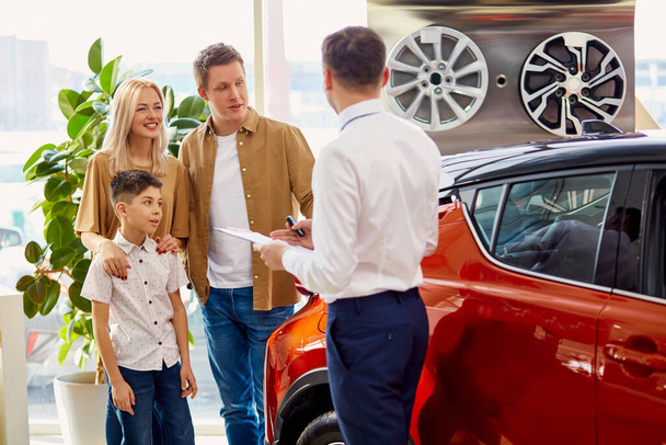 affable salesman consult customers in cars dealership - Foto, Bild