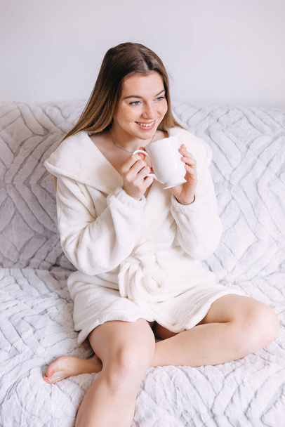 aantrekkelijke jonge vrouw genieten van haar ochtend koffie thuis - Foto, afbeelding
