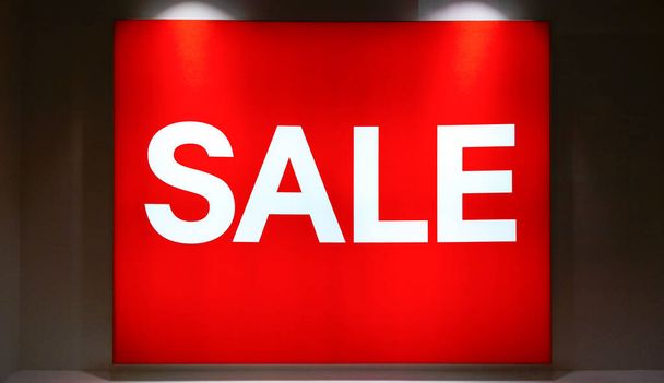 wyświetlacz okna z białym tekstem "'SALE'" na czerwonym tle kolor, sprzedaż baner light box w sklepie mody w centrum handlowym w czarny piątek na Boże Narodzenie - Zdjęcie, obraz