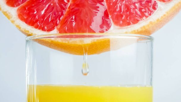 ガラスのグレープフルーツ片から落ちるジュース液滴のクローズアップイメージ - 写真・画像