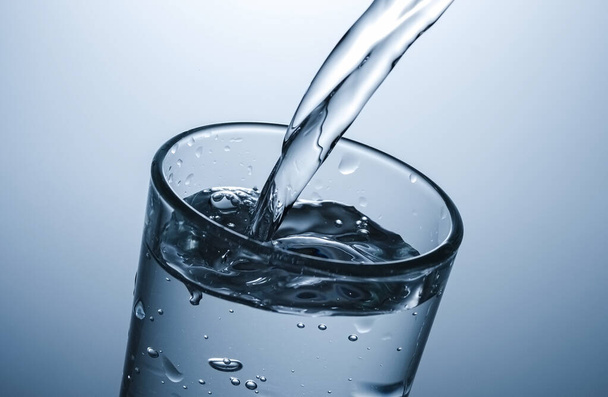 Gießen perlenden Wassers in ein Glas in Nahaufnahme auf den Rand des fast vollen Glases mit sprudelnden Blasen - Foto, Bild