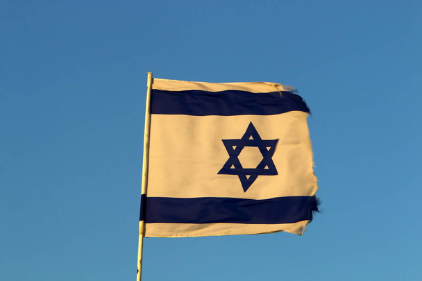wit-blauwe vlag van de staat Israël met een ster van David zwaaiend in de wind  - Foto, afbeelding