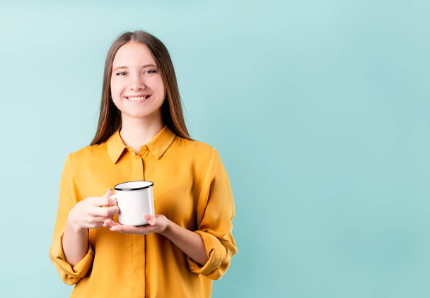 Mladá běloška žena na sobě pití kávy nebo čaje přes modré pozadí - Fotografie, Obrázek