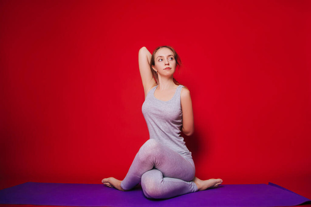 Атлетична йога, вродлива молода дівчина, що практикує Ека Паду Гарудасан. Жінка в чорному спортивному вбранні на червоному фоні - Фото, зображення