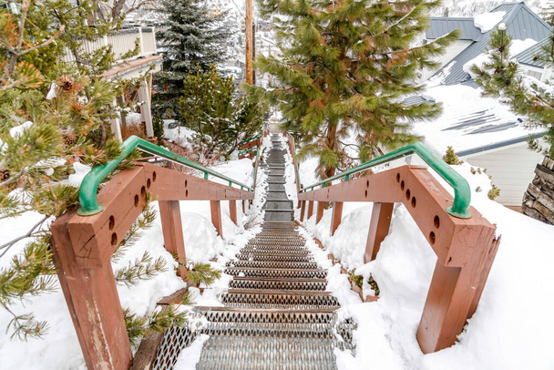 Stairway on hill overlooking rooftops homes and trees with fresh snow in winter - Photo, Image