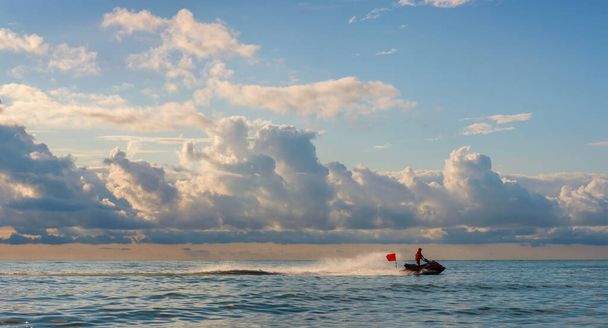 Περιπολίες ναυαγοσώστη θάλασσα ακτή σε ένα τζετ σκι με κόκκινη σημαία, όμορφο συννεφιασμένο ουρανό φόντο - Φωτογραφία, εικόνα