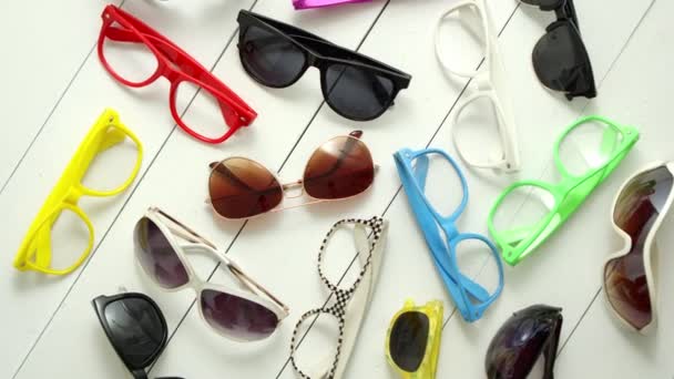 Colección de gafas de sol de varios estilos y colores y monturas capturadas desde arriba
. - Metraje, vídeo