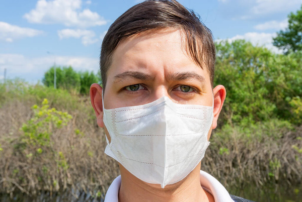 Retrato de cara de joven con máscara médica se encuentra en la naturaleza. primer plano, virus corona
 - Foto, imagen