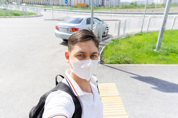 Молодой человек в защитной медицинской маске ходит по городу. Карантин, коронавирус
 - Фото, изображение