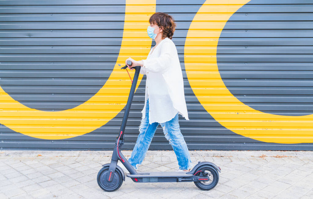 New normal. Woman girl with a mask using an electric scooter. Woman using electric and ecological transport Safety and pandemic concept. Coronavirus devices. Social distance. Coronavirus. - 写真・画像