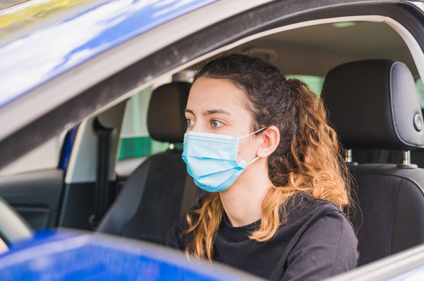 新しい正常よ。乗客と車を運転する医療面マスクを持つ女性ドライバー。健康保護。マスクの安全性とパンデミックの概念によって保護車の中で家族。コロナウイルス。社会的距離. - 写真・画像