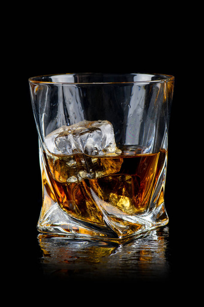 Glas whisky of andere alcohol met ijsblokjes op zwarte ondergrond - Foto, afbeelding