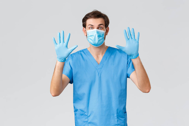 Covid-19 、隔離、病院、医療従事者の概念。医療用マスク、手袋、スクラブのフレンドリーな医師は、彼の手、番号10を示し、コロナウイルスから保護するための安全対策を説明します - 写真・画像