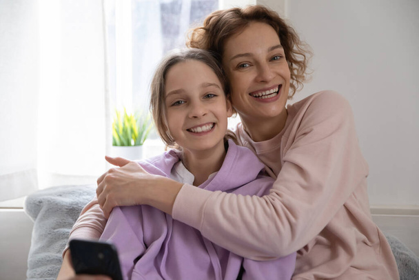 Portrait of happy mom and teen daughter hugging at home - Фото, зображення