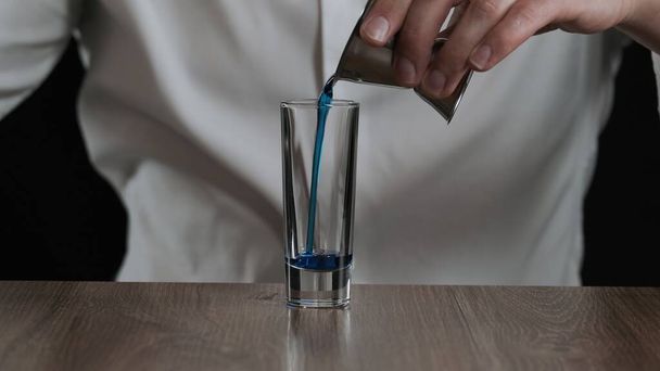 Barman giet blauwe curacao drank in glas van jigger. Sluiten. - Foto, afbeelding