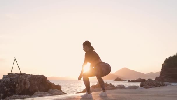 femme sportive étirement séance d'entraînement sur la plage coucher de soleil - Séquence, vidéo