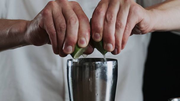 Making alcoholic cocktail. The bartender throws up sliced lime on knifes blade - Photo, Image