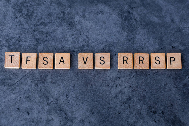 "TFSA vs RRSP "spelled out in wooden letter tiles on a dark rough background
 - Фото, изображение