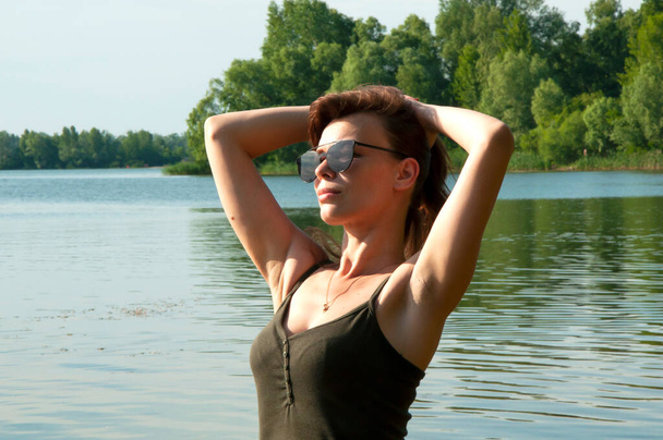 Zbliżenie ładna kobieta nad rzeką w letni słoneczny dzień. Odpocznij w lecie. Koncepcja piękna i szczęścia. - Zdjęcie, obraz