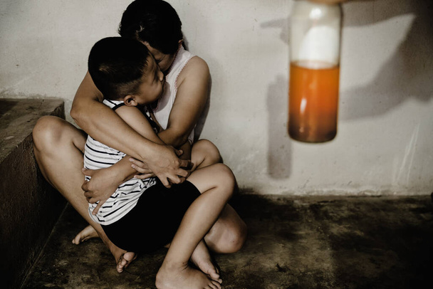 Плаче молода жінка, обіймаючи сина. Жінка боїться чоловіка, який тримає пляшку алкоголю
. - Фото, зображення