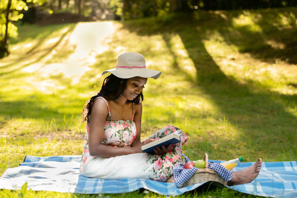 Çekici Afrikalı kadın piknikte kitap okuyor. - Fotoğraf, Görsel