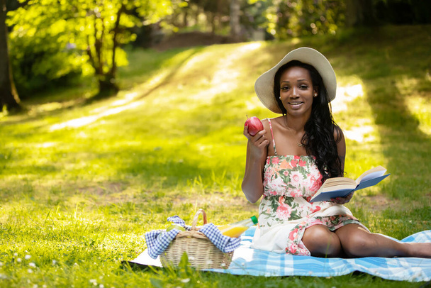 Attractive african woman is reading a book at picnic - Φωτογραφία, εικόνα