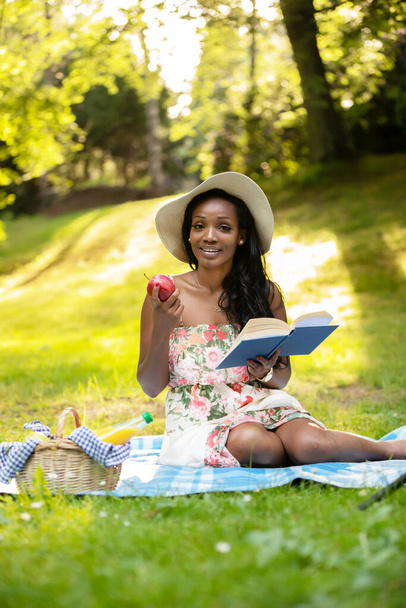 Attractive african woman is reading a book at picnic - Fotoğraf, Görsel