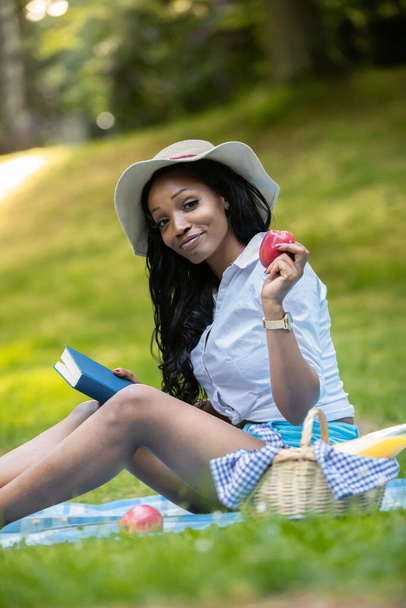 Attractive african woman is reading a book at picnic - Fotó, kép