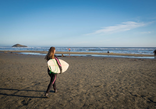 Pacific Rim National Park Reserve, Canadá, 25 de setembro de 2016 - Uma surfista feminina sai para o oceano em uma das principais mecas de surf do Canadá, Long Beach, perto da aldeia de Tofino
. - Foto, Imagem