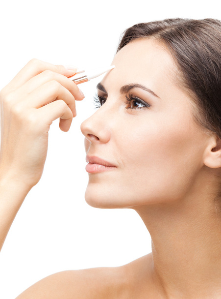 Smiling woman applying concealer on face, isolated - Foto, Imagen