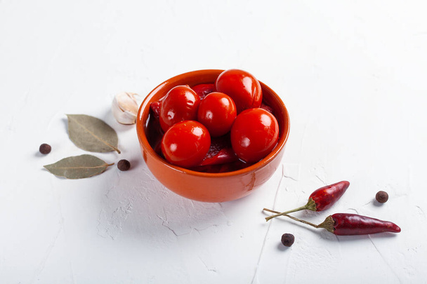 Pomodori rossi salati con ingredienti su una tavola bianca
 - Foto, immagini