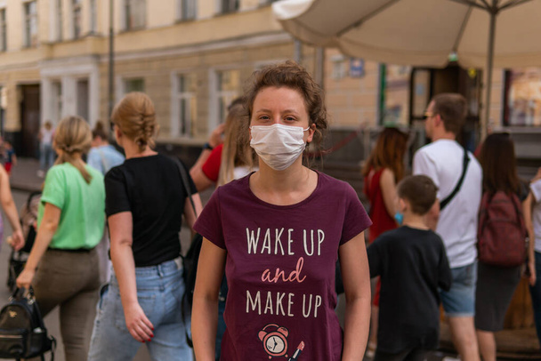 Une jeune jolie fille masquée est debout dans une foule dans une rue, beaucoup de gens marchent masques wihtout
 - Photo, image
