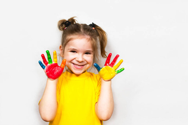 Belle petite fille avec les mains dans la peinture sourit dans un T-shirt jaune. Créativité des enfants
. - Photo, image