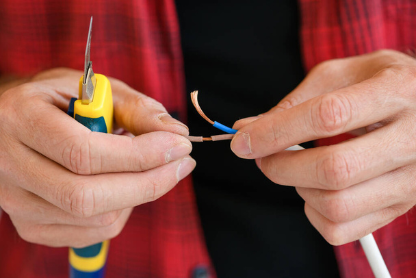 Manos masculinas con cuchillo y cables eléctricos
 - Foto, Imagen