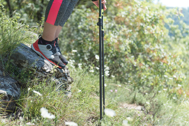 Woman hiking in the mountains, adventure and exercise. Nordic walking legs and poles in summer nature. Active people outdoor - Photo, Image