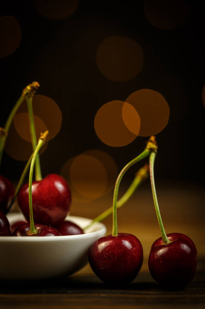 Ripe cherries on a brown table, beautiful bokeh - Foto, Imagen