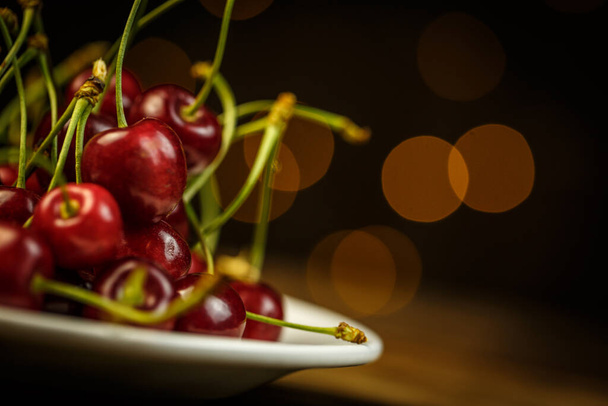Ripe cherries on a brown table, beautiful bokeh - Foto, Imagem