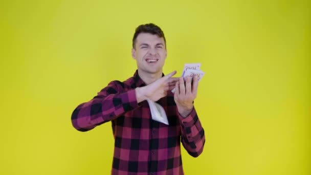 Rich man in a pink plaid shirt throws money on a yellow background - Video