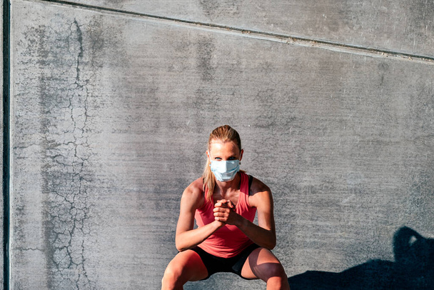 υπαίθριο οριζόντιο πορτρέτο μιας υγιούς αθλητικής γυναίκας με προστατευτική μάσκα - Φωτογραφία, εικόνα