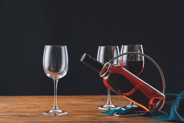 Держатель с бутылкой вина и бокалами на столе
 - Фото, изображение