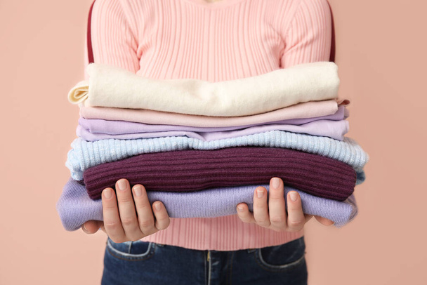 Mujer con pila de ropa limpia sobre fondo de color, primer plano
 - Foto, Imagen