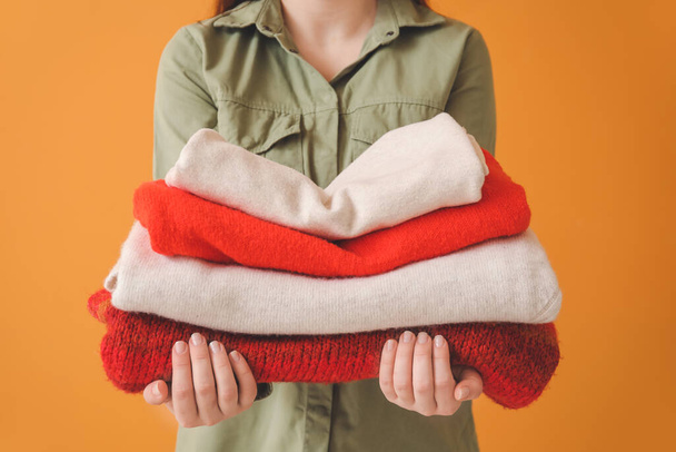 Woman with stack of clean clothes on color background, closeup - 写真・画像