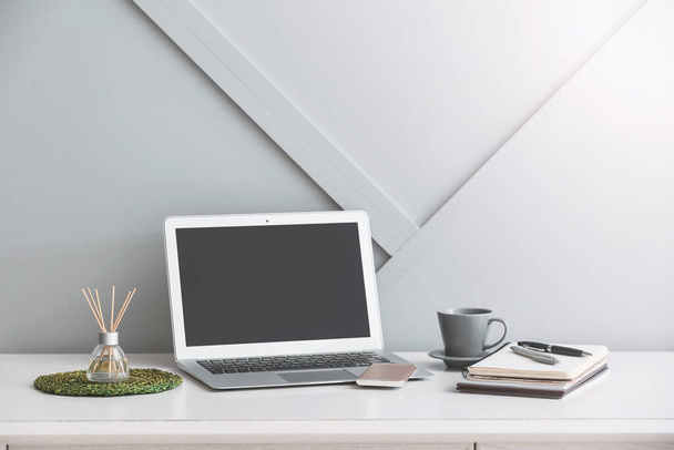 Диффузер, ноутбук и канцелярские принадлежности на столе
 - Фото, изображение