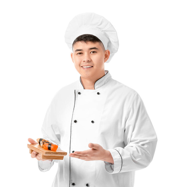 Knappe Aziatische chef met sushi broodjes op witte achtergrond - Foto, afbeelding