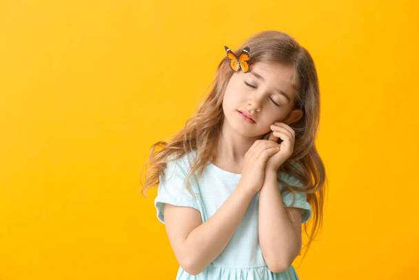 Nettes kleines Mädchen mit Schmetterling auf farbigem Hintergrund - Foto, Bild