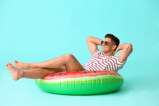Young man with inflatable ring on color background - Foto, imagen