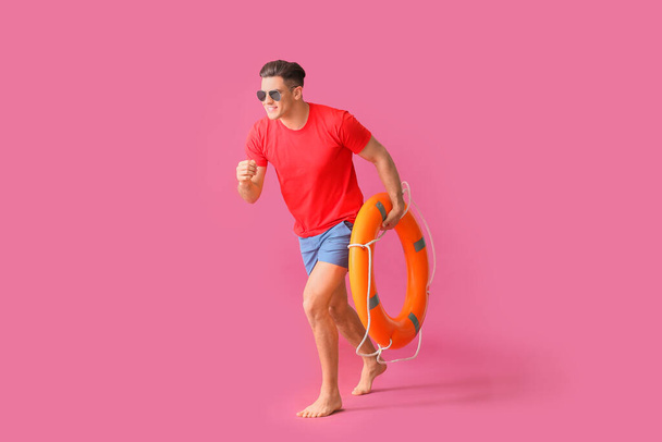 Laufender Strandretter mit Rettungsring auf farbigem Hintergrund - Foto, Bild