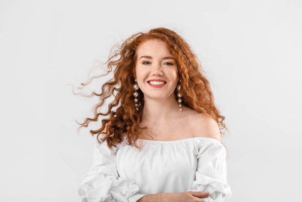 Portrait of beautiful redhead woman on light background - Foto, Imagen